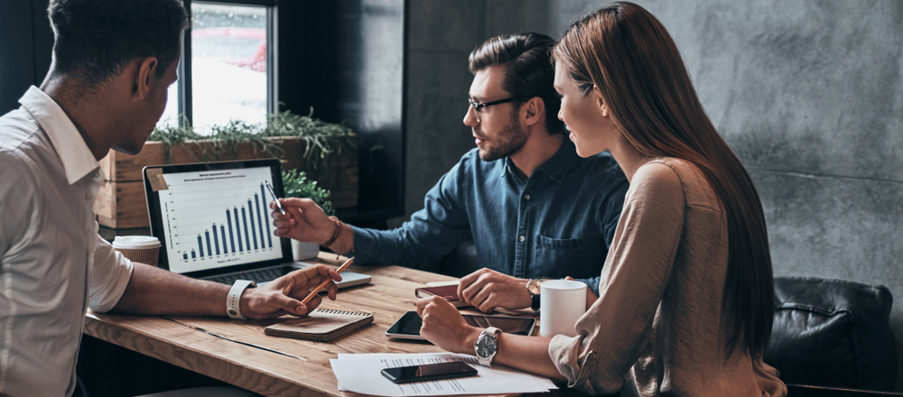 Group of young confident business people analyzing data using computer while spending time in the office