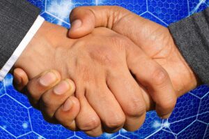 Two business owners shaking hands across a conference table after agreeing the terms of a contingent earn-out payment.